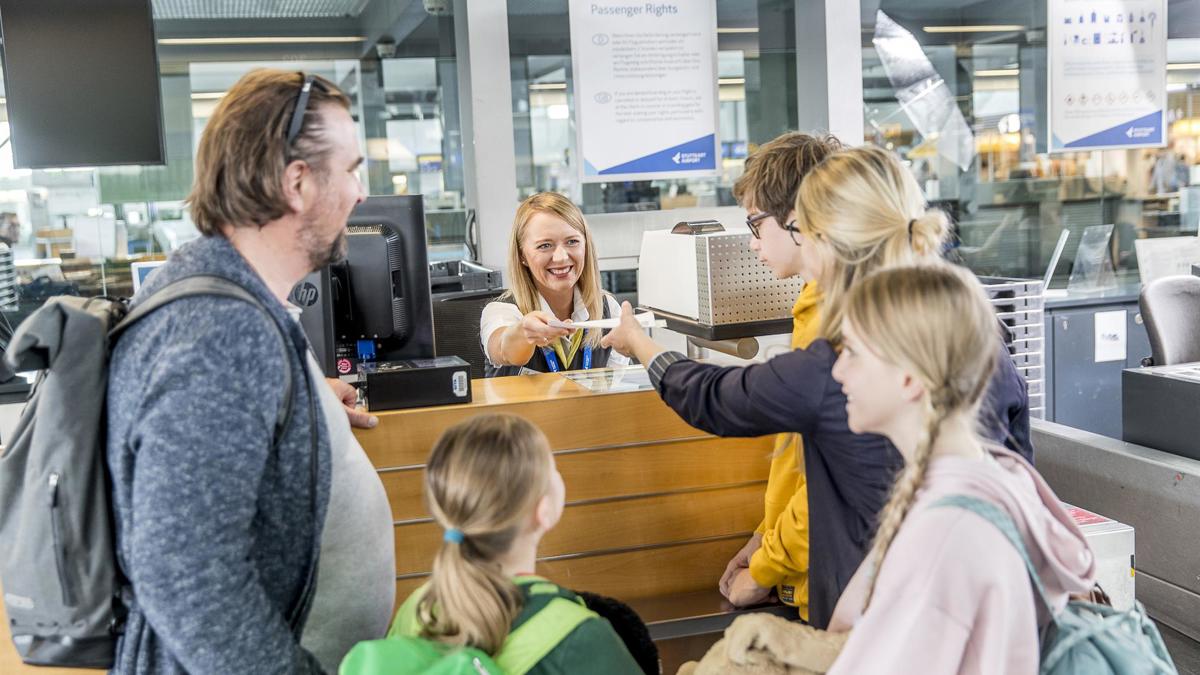 Mitarbeiter gibt Passagieren am Schalter ihre Bordkarten