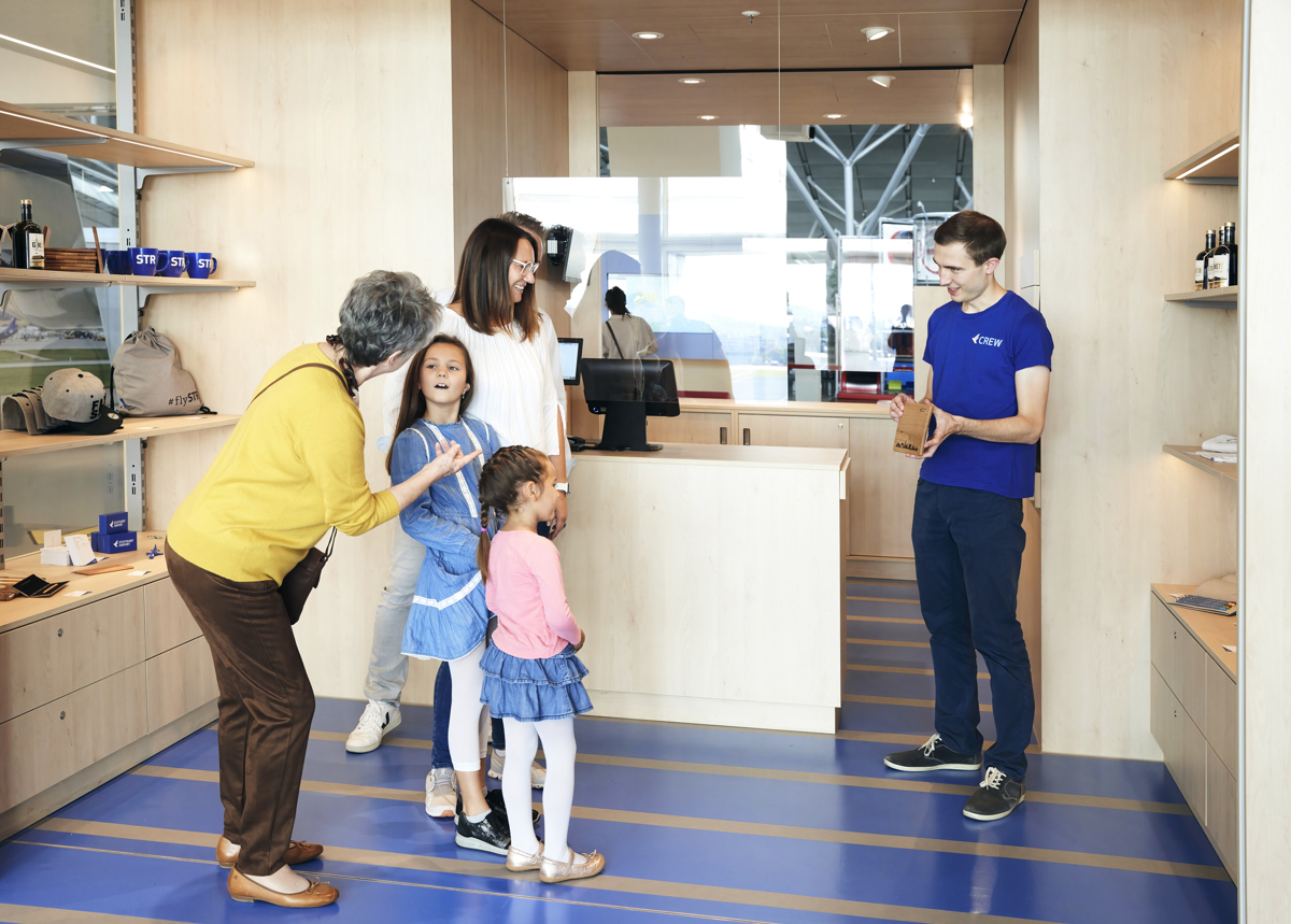 Mitarbeiter berät Familie beim Einkauf im Shop der Erlebniswelt